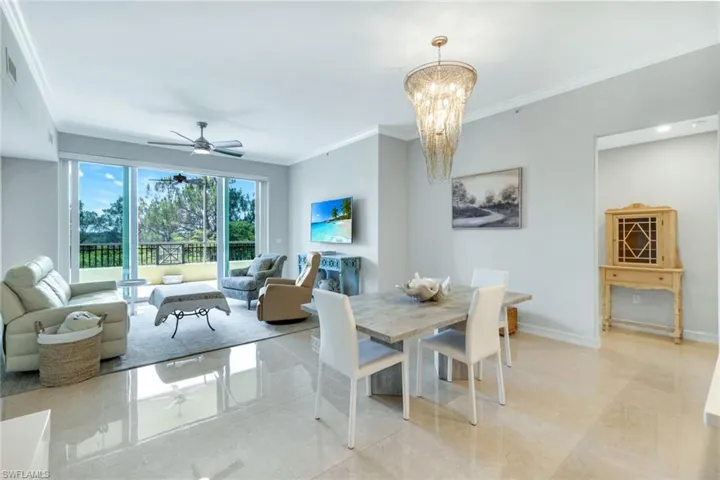 Great Room and Dining room featuring ornamental molding, a chandelier, ceiling fan, baseboards, and light tile patterned flooring