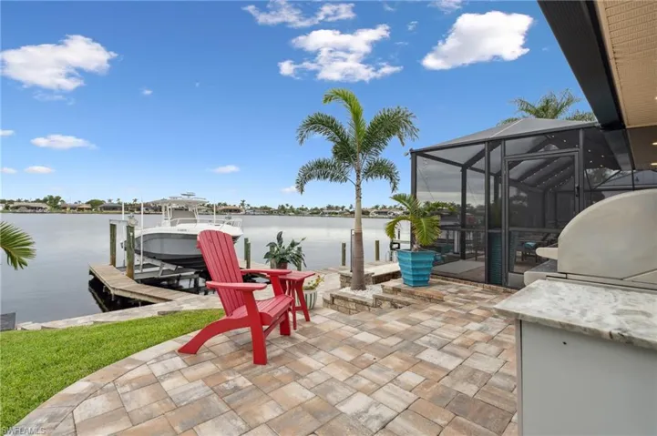 View of patio with a boat dock, a water view, grilling area, and a lanai