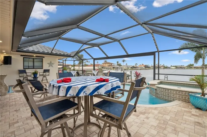 View of patio featuring a swimming pool with hot tub and glass enclosure