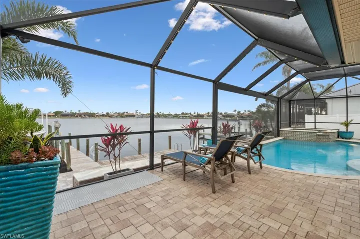 View of pool with a lanai, a patio area, an in ground hot tub, and a water view