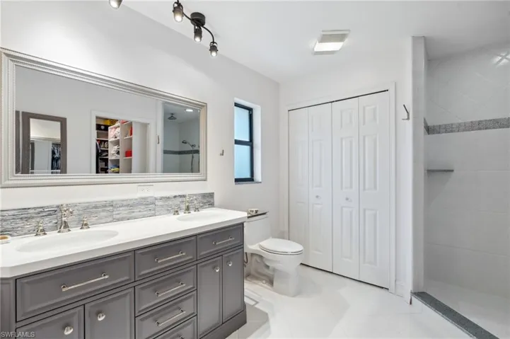 Bathroom featuring tile patterned floors, tiled shower, backsplash, and vanity