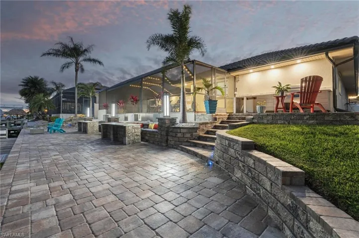 Patio terrace at dusk featuring a fire pit and a lawn