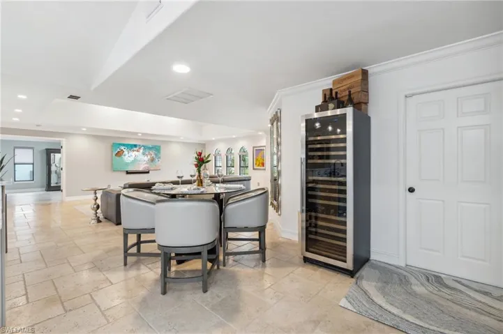 Dining area with ornamental molding, beverage cooler, and indoor bar