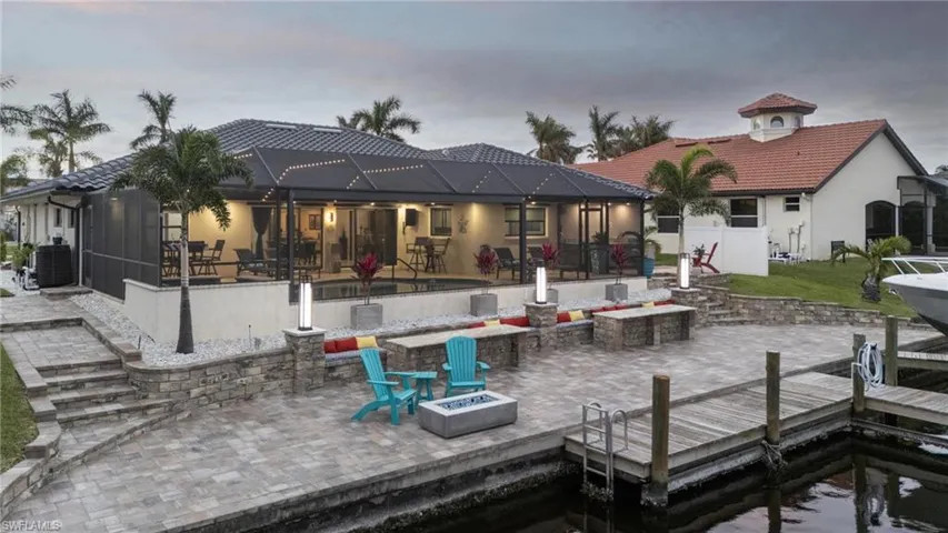 Back house at dusk featuring central air condition unit, a fire pit, a lanai, and a patio area