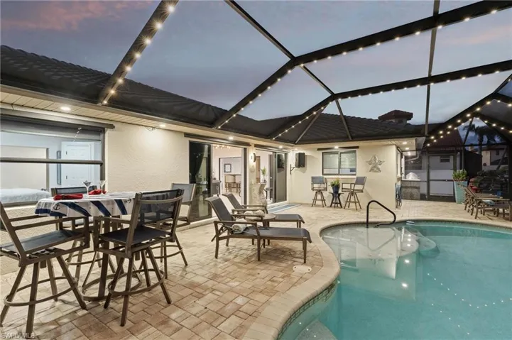 Pool at dusk featuring a patio and glass enclosure