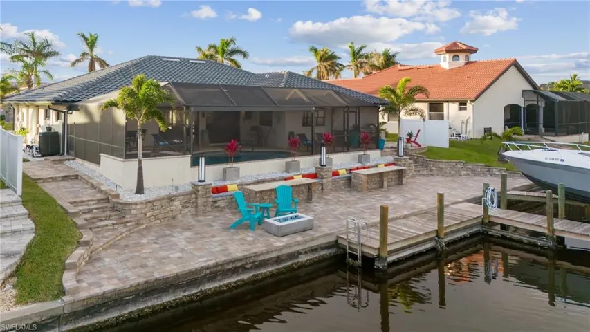 Rear view of property with a fire pit, a lanai, a patio, and a water view