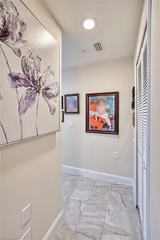 Hallway featuring baseboards and light marble finish flooring