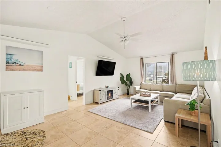 Spacious living area featuring vaulted ceilings, tile flooring, and a ceiling fan