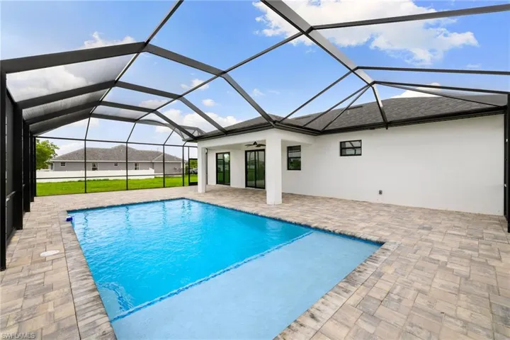 Outdoor pool with a patio, ceiling fan, and glass enclosure