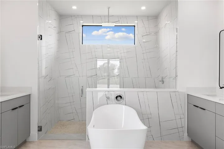 Full bathroom featuring vanity, a stall shower, a freestanding tub, and recessed lighting