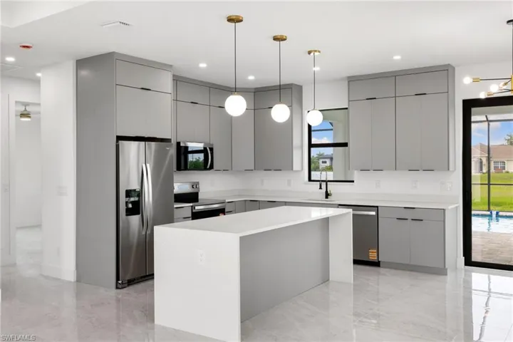 Kitchen with appliances with stainless steel finishes, gray cabinets, modern cabinets, a center island, and light countertops