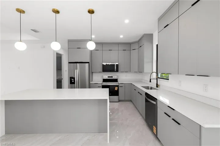 Kitchen featuring stainless steel appliances, gray cabinetry, light marble finish floors, modern cabinets, and light countertops