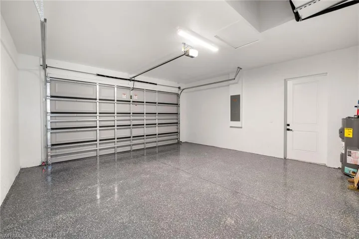 Garage with electric panel, electric water heater, and a garage door opener