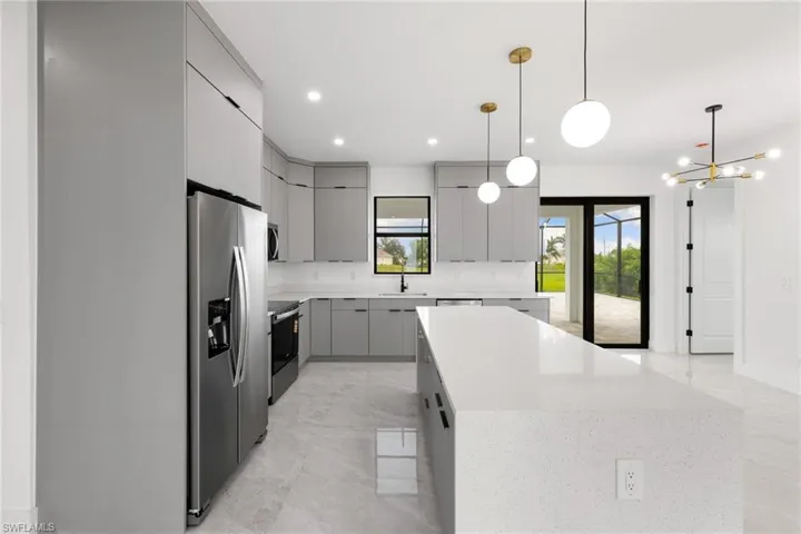 Kitchen featuring appliances with stainless steel finishes, gray cabinetry, a center island, modern cabinets, and a chandelier