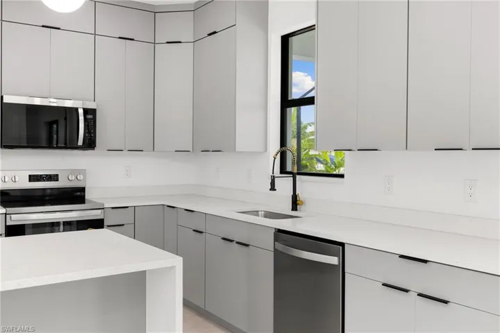 Kitchen with appliances with stainless steel finishes, gray cabinetry, and modern cabinets