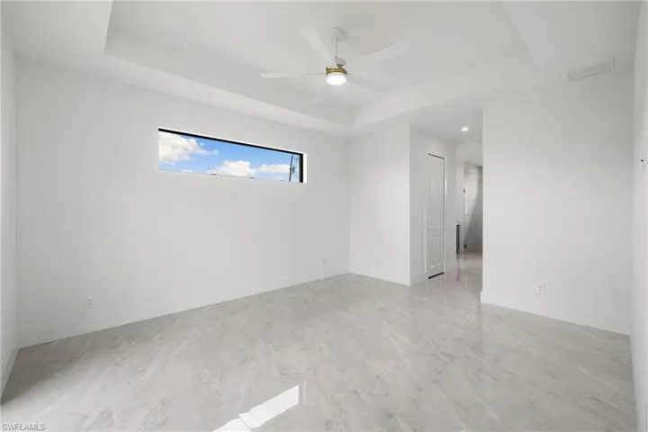 Empty room with a tray ceiling, a ceiling fan, and recessed lighting