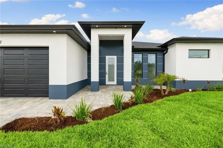 View of front facade with stucco siding, a front lawn, and a garage