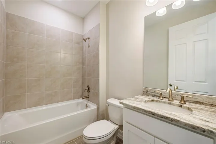Full bathroom featuring tile patterned floors, toilet, vanity, and tiled shower / bath