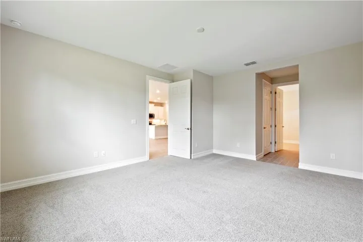 Unfurnished bedroom featuring light carpet and ensuite bath