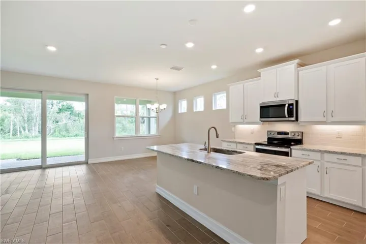 Kitchen featuring white cabinetry, appliances with stainless steel finishes, sink, decorative backsplash, and a center island with sink
