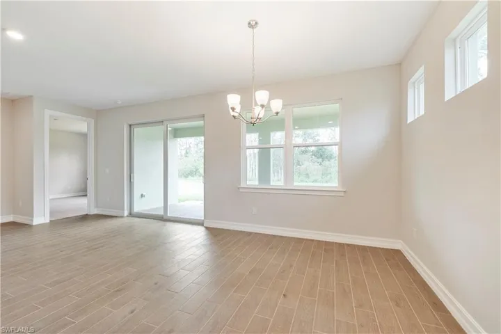 Unfurnished room featuring an inviting chandelier, light wood-type flooring, and a wealth of natural light