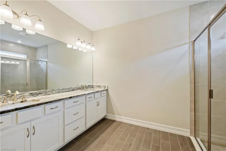 Bathroom featuring an enclosed shower and dual bowl vanity