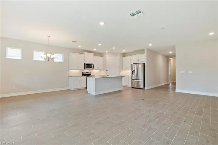 Kitchen featuring a notable chandelier, a center island with sink, white cabinets, appliances with stainless steel finishes, and sink