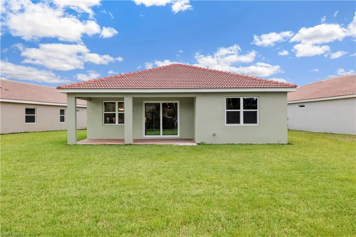 Rear view of house featuring a patio and a lawn