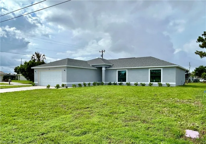 Single story home featuring a garage and a front lawn