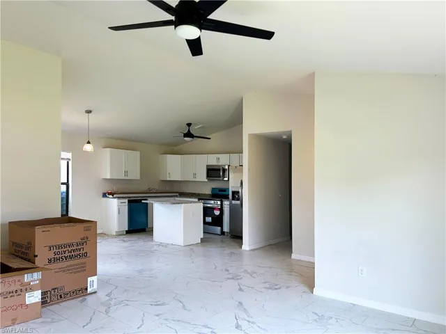 Kitchen with decorative light fixtures, light tile flooring, stainless steel appliances, ceiling fan, and white cabinetry