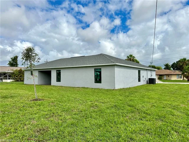View of side of property featuring a yard and central AC unit