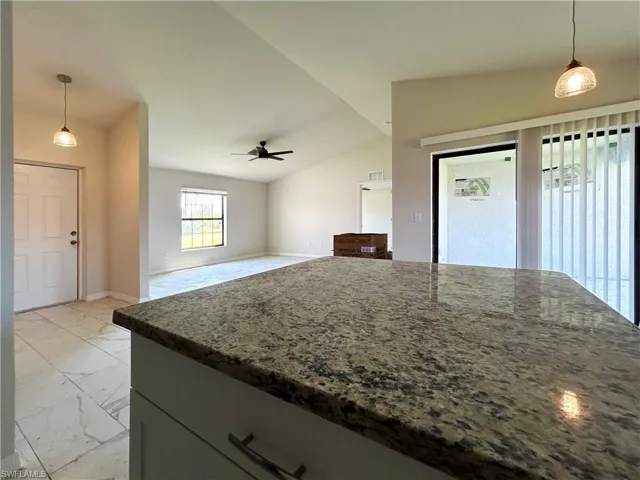 Kitchen with lofted ceiling, ceiling fan, light tile floors, and pendant lighting