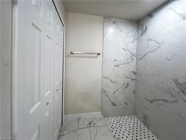Bathroom featuring tiled shower and tile floors