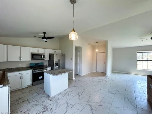 Kitchen featuring stainless steel appliances, vaulted ceiling, ceiling fan, and decorative light fixtures
