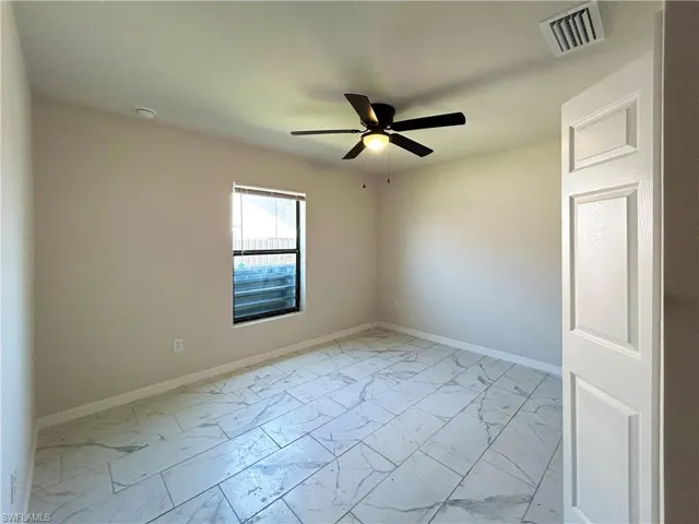 Empty room with ceiling fan and light tile floors