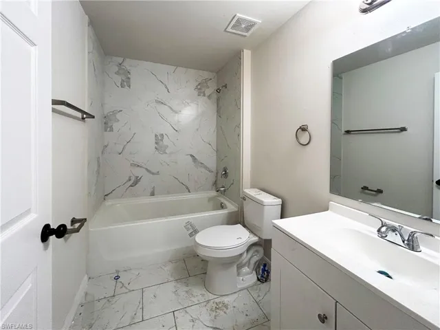 Full bathroom with tile flooring, oversized vanity, toilet, and tiled shower / bath combo