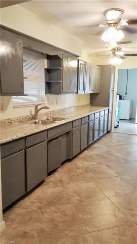 Kitchen with tons of cabinets, gray cabinetry, dishwasher  and ceiling fans,.