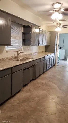 Kitchen featuring ceiling fan, open shelves, gray cabinets, and washer / dryer