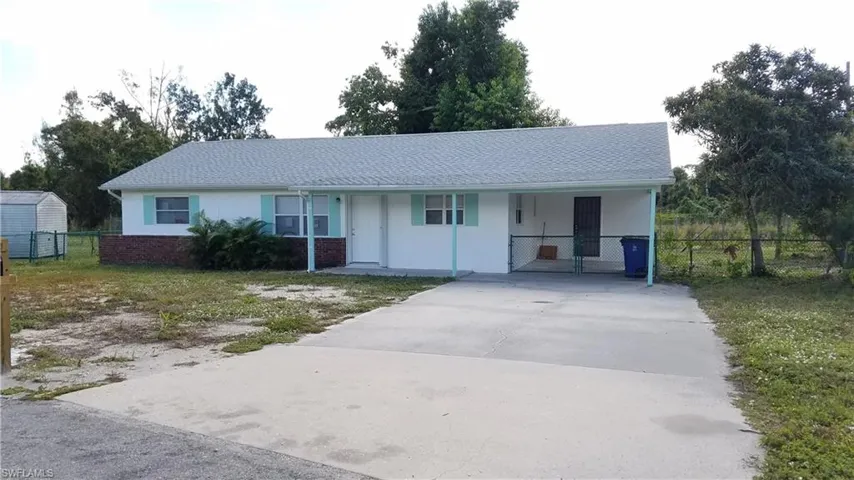 Ranch-style house with driveway, an attached carport, covered porch, and stucco siding