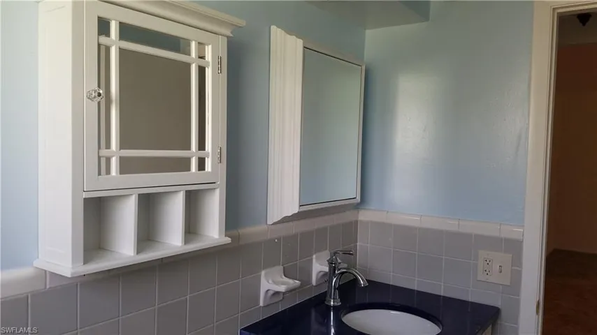 Bathroom featuring vanity, backsplash, and tile walls