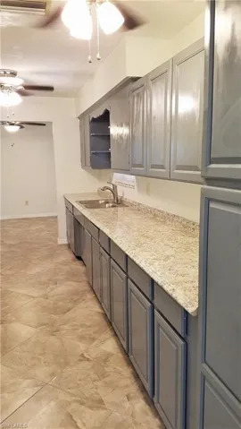 Kitchen with ceiling fans, and loads of gray  cabinets plus pantry