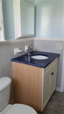 Bathroom featuring tile walls, vanity, and a wainscoted wall