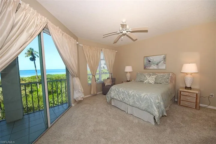 Carpeted bedroom featuring access to exterior, a textured ceiling, ceiling fan, and a water view
