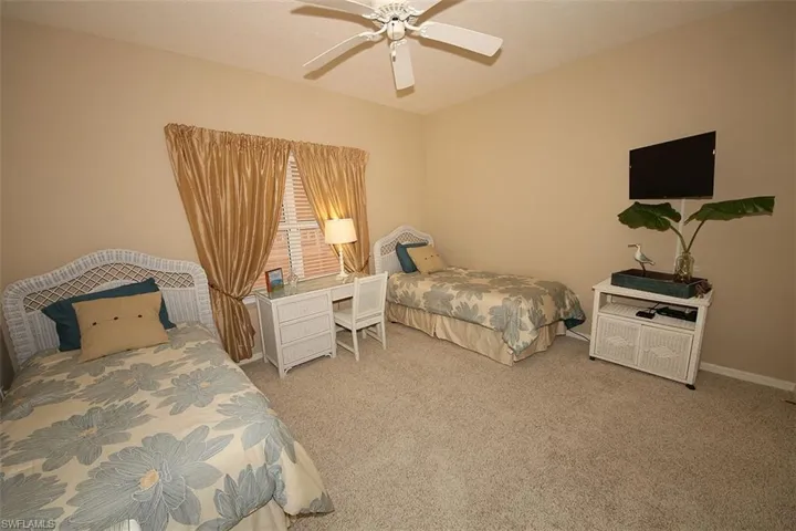 Carpeted bedroom with ceiling fan and baseboards