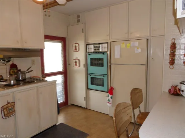 Kitchen featuring freestanding refrigerator, light countertops, a ceiling fan, and white cabinets