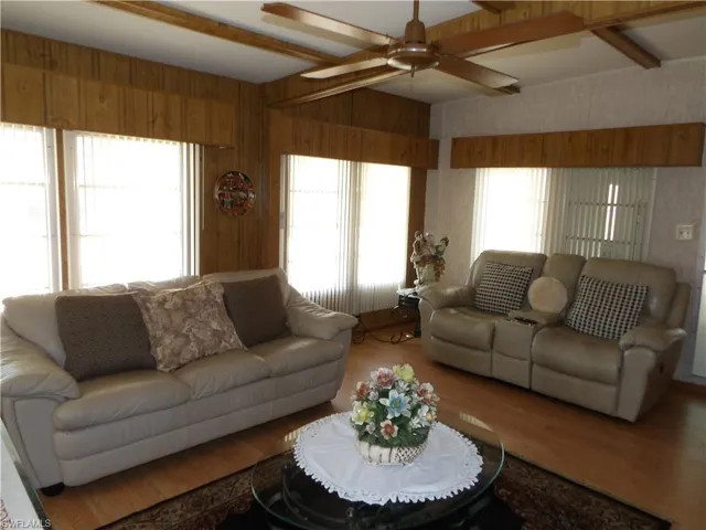 Living area with beam ceiling, a ceiling fan, and wood finished floors