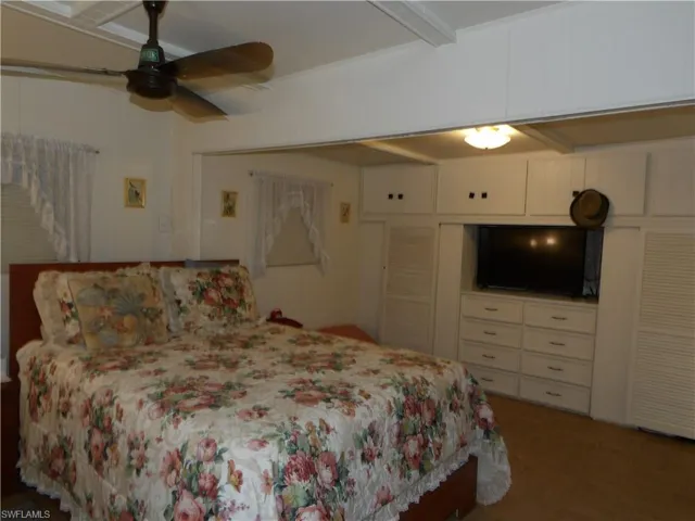 Bedroom with a closet, a ceiling fan, beamed ceiling, and parquet flooring