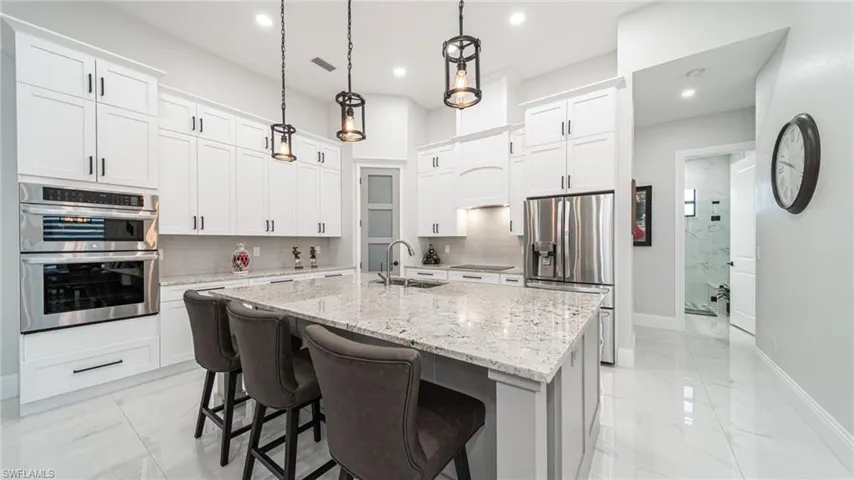 Kitchen featuring stainless steel appliances, tasteful backsplash, a kitchen island with sink, sink, and pendant lighting