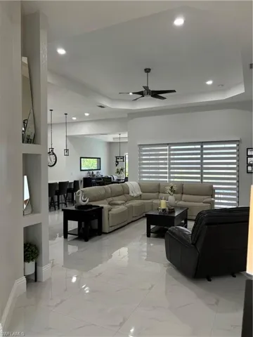 Tiled living room with ceiling fan and a raised ceiling