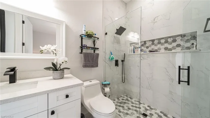 Bathroom with a shower with shower door, vanity, and toilet